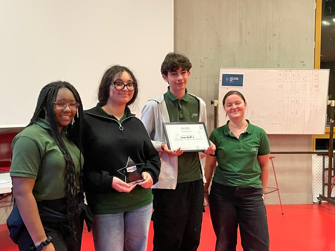 Quatre jeunes récompensés posent avec leur diplôme et leur trophée lors d'une remise de prix
